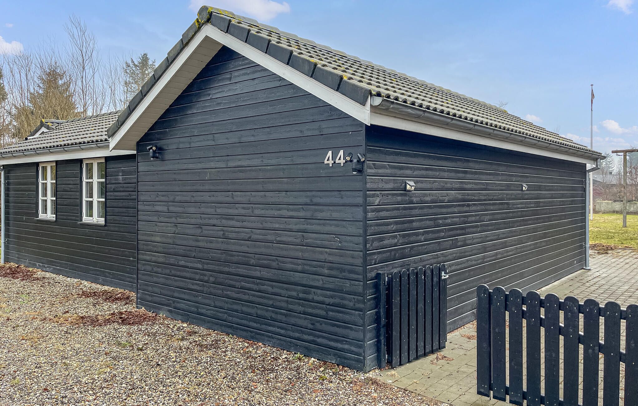 A dark wooden building with a gabled roof, a garage door, and a small window.