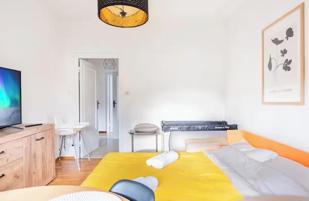 Een hotelkamer met een bed, een bureau, een stoel, een televisie en een lijst aan de muur.