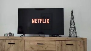 Un televisore con il logo Netflix sullo schermo, posato su un mobile in legno con cassetti.