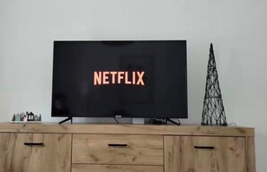 Ein Fernseher mit Netflix-Logo auf dem Bildschirm, auf einer Holzkommode mit Schubladen platziert.