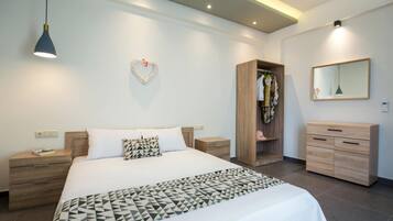 A modern bedroom with a bed, bedside tables, a wardrobe, a mirror, and a heart-shaped decoration on the wall.