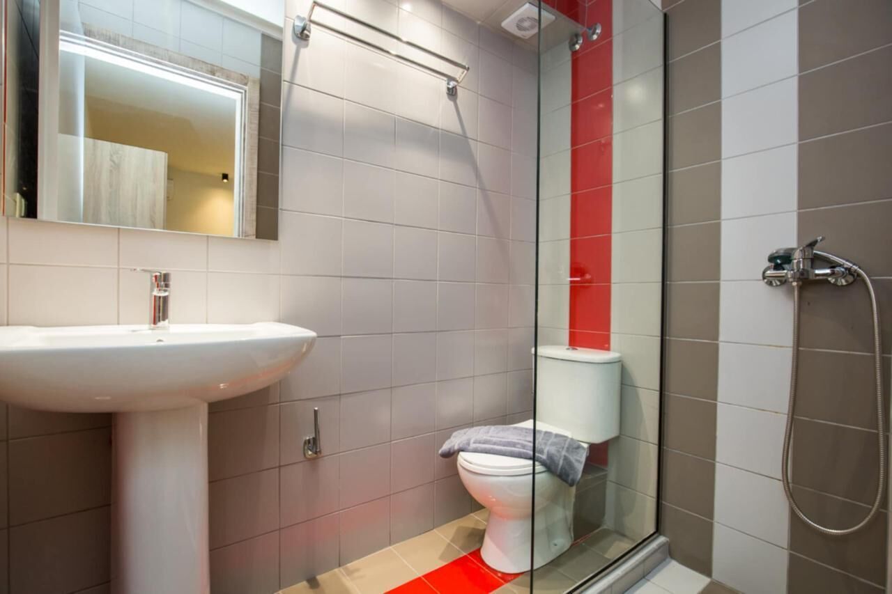 Une salle de bain avec un lavabo blanc, une cabine de douche en verre et des toilettes.