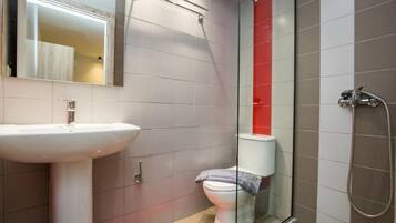 Une salle de bain avec un lavabo blanc, une cabine de douche en verre et des toilettes.