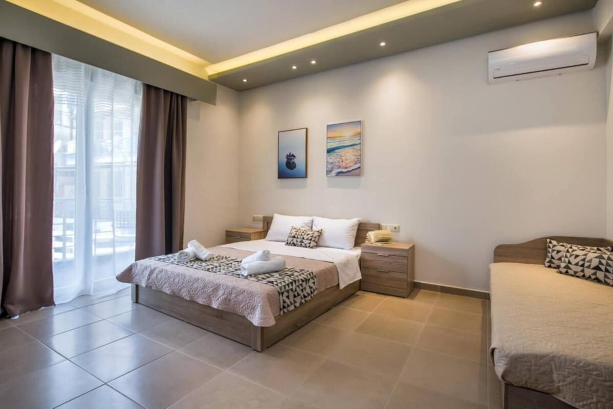 A bedroom with a bed, bedside tables, an air conditioning unit, and a window with curtains.