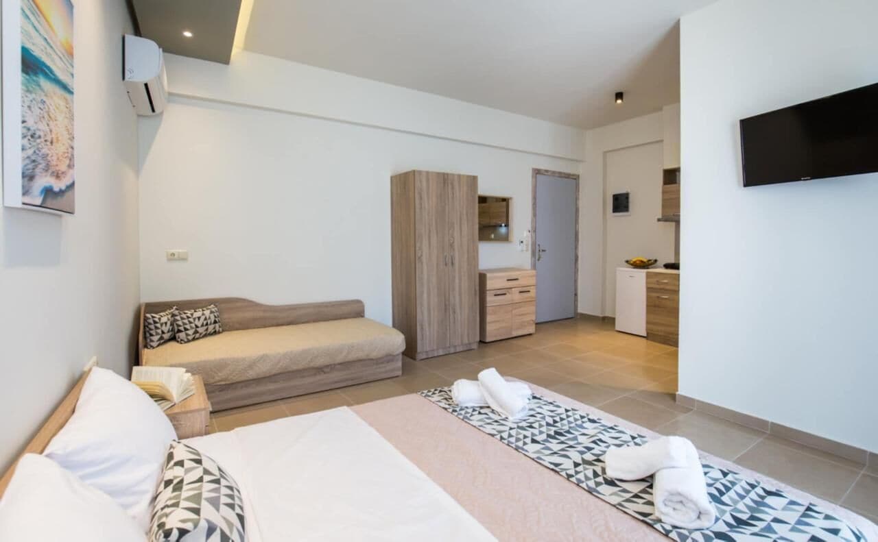 Ein modernes Hotelzimmer mit Bett, Sofa, Kleiderschrank, Fernseher und Bad.