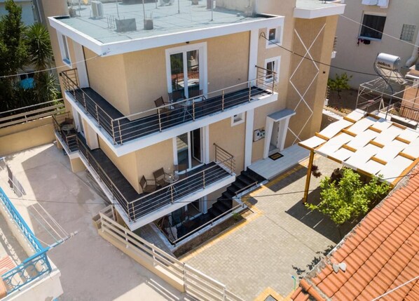 A multi-story building with balconies, a covered outdoor seating area, and a rooftop terrace. - Studios&Apartments Elisabeta (Limenaria)