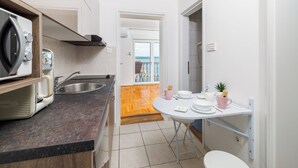 Eine kompakte Küchenzeile mit Mikrowelle, Spüle und Essbereich mit Tisch und Stühlen.