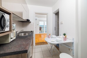 Eine kompakte Küchenzeile mit Mikrowelle, Spüle und Essbereich mit Tisch und Stühlen.