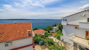 Ein Küstenwohngebiet mit Terrakotta-Dächern, weißen Gebäuden und Blick auf das Meer.