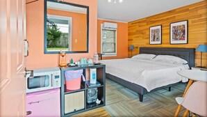 A bedroom with a bed, a desk, a chair, a microwave, a refrigerator, a mirror, and artwork on the wall. - Cozy Contemporary Space in St Augustine (St. Augustine)