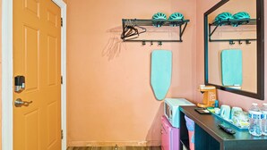 A bathroom with a peach-colored wall, a door, a mirror, a towel rack, a sink, a countertop with toiletries, and a small heater. - Cozy Contemporary Space in St Augustine (St. Augustine)