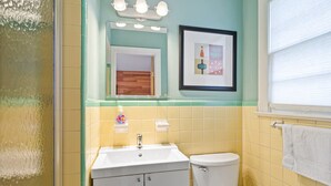 A bathroom with a sink, toilet, and a framed picture on the wall. - Cozy Contemporary Space in St Augustine (St. Augustine)