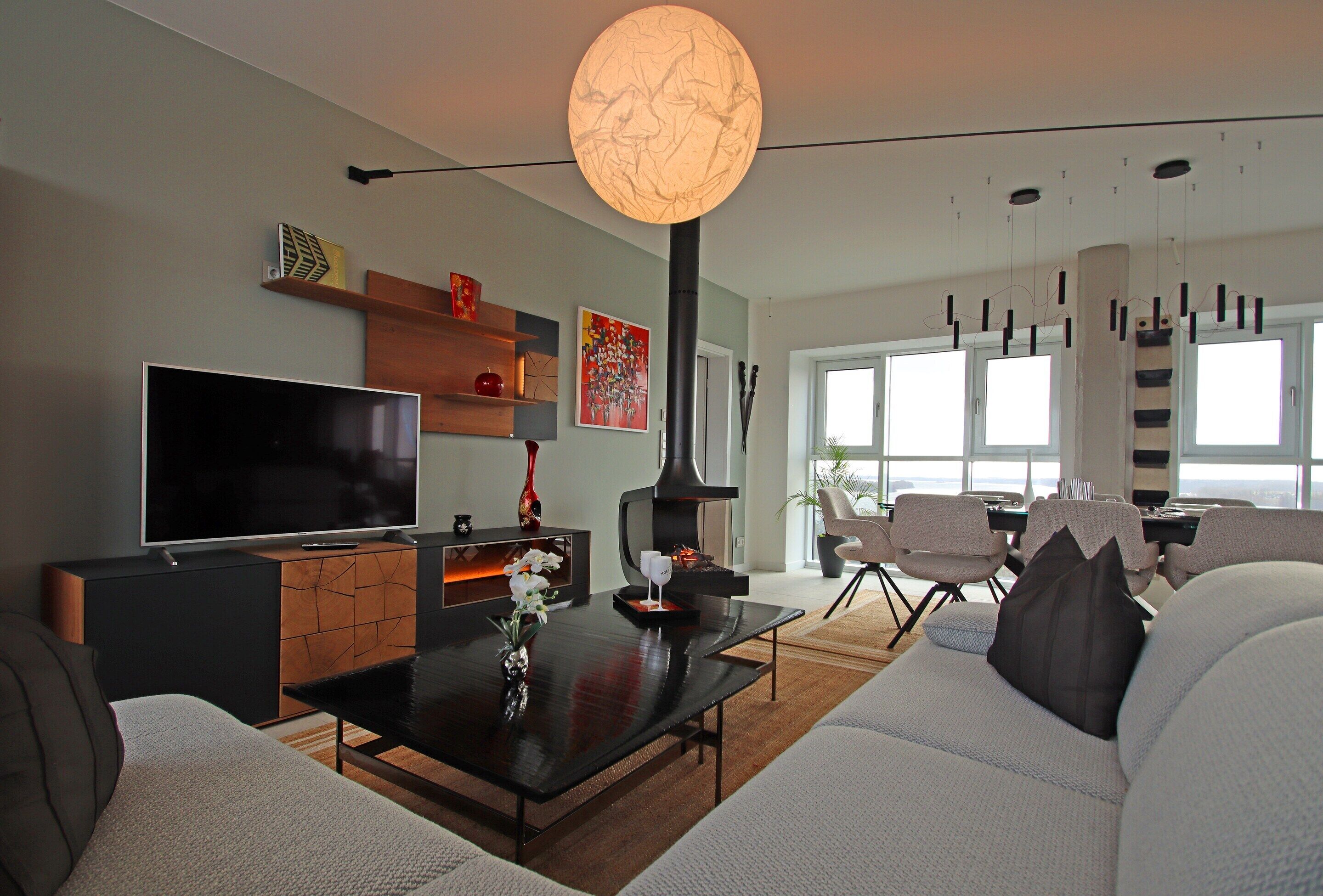 A modern living room with a flat-screen TV, a fireplace, and a dining area with chairs and a table.