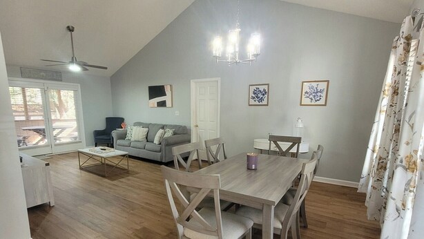A dining area with a wooden table and chairs, a chandelier, and a ceiling fan. - Cozy home featuring a screened-in porch and access to a refreshing pool. Your oasis awaits!! (Ocean Pines)