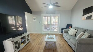 A living room with a TV, a ceiling fan, a white coffee table, and a grey sofa. - Cozy home featuring a screened-in porch and access to a refreshing pool. Your oasis awaits!! (Ocean Pines)