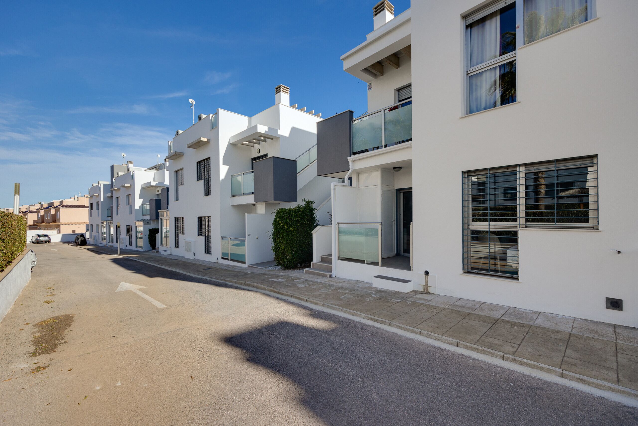 A row of modern, white buildings with balconies and large windows.