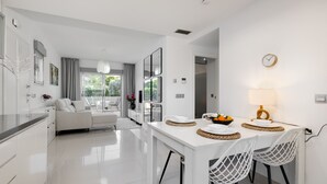 A modern kitchen with a dining area, white cabinetry, and a view to the outside. - Groundfloor Amay Punta Prima pool/sauna (Torrevieja)