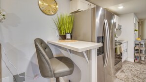 Una cucina moderna con frigorifero integrato, orologio a parete e un piccolo tavolo con una pianta.