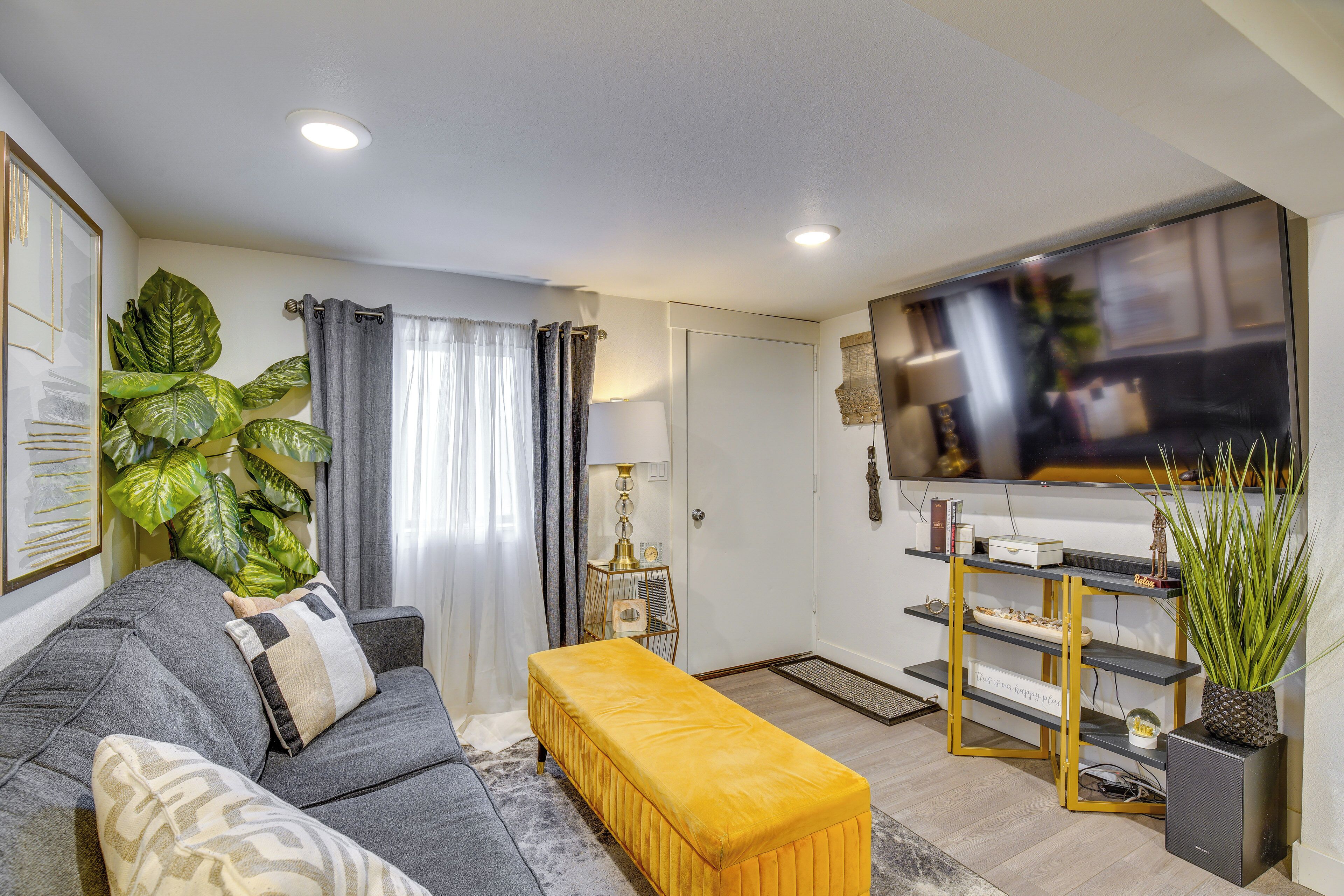 A living room with a sofa, a bench, a TV, a plant, and a shelf.