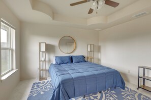 A bedroom with a bed, a ceiling fan, a window, and a patterned rug. - Easy Living in Brownsville! Home Near Med Center (Brownsville)