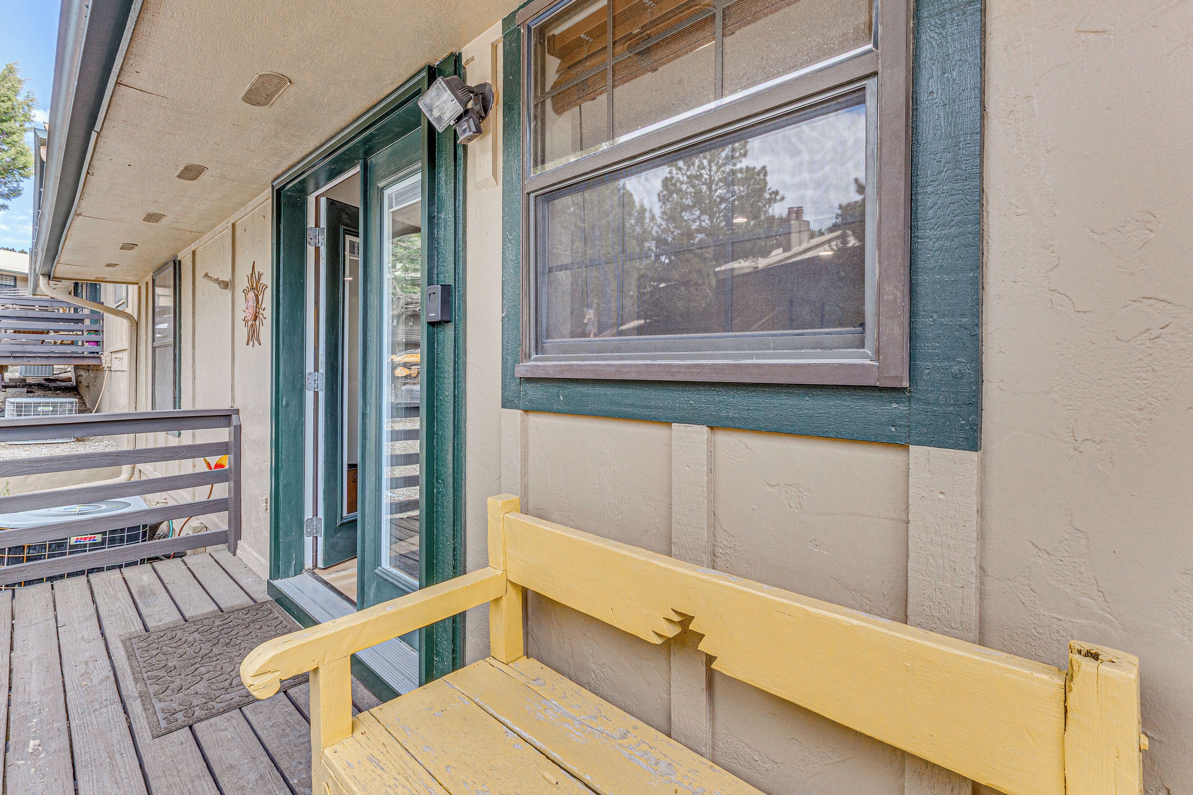 A wooden bench outside a building with a door and windows.
