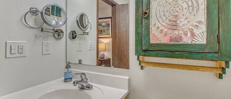 A bathroom with a sink, mirrors, a toilet, and a decorative metal plate.