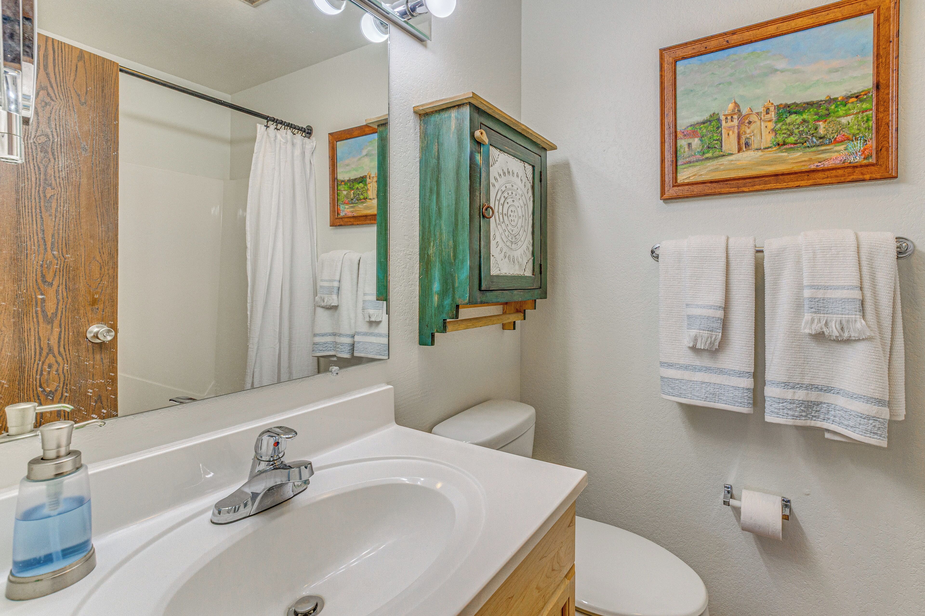 A bathroom with a sink, mirror, toilet, and towels.