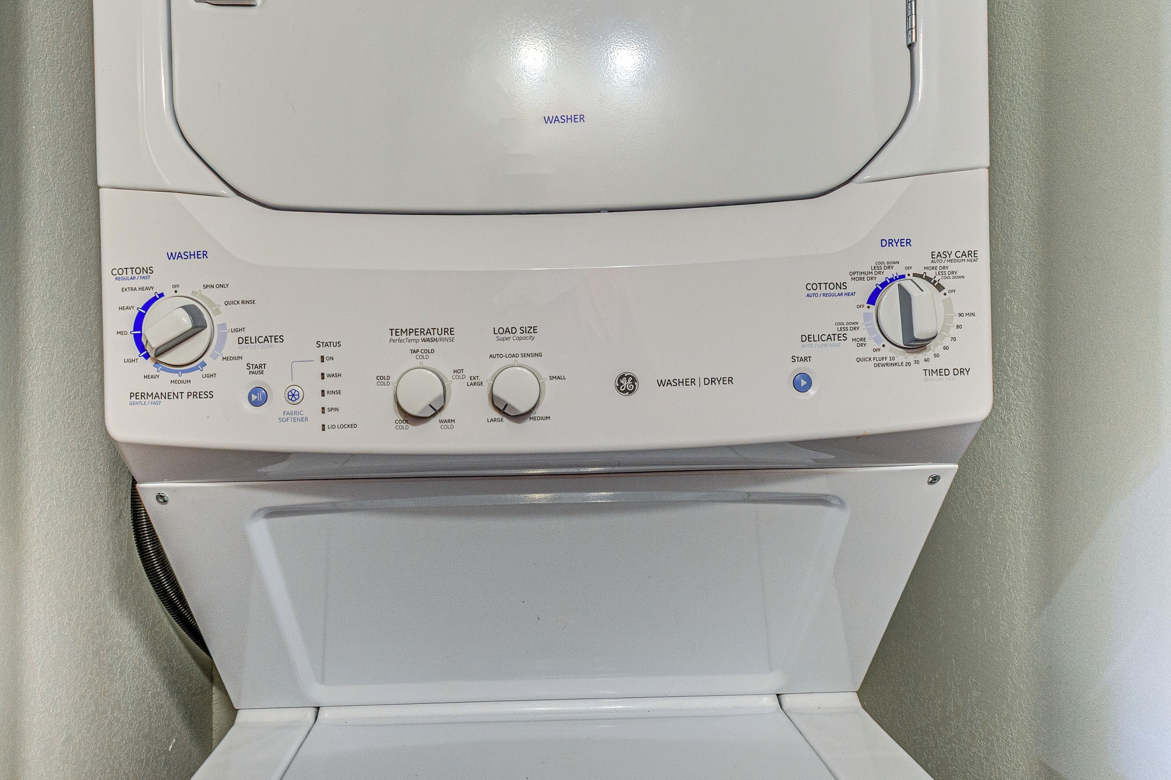 A front view of a washer and dryer unit with control knobs for temperature, load size, and spin settings.