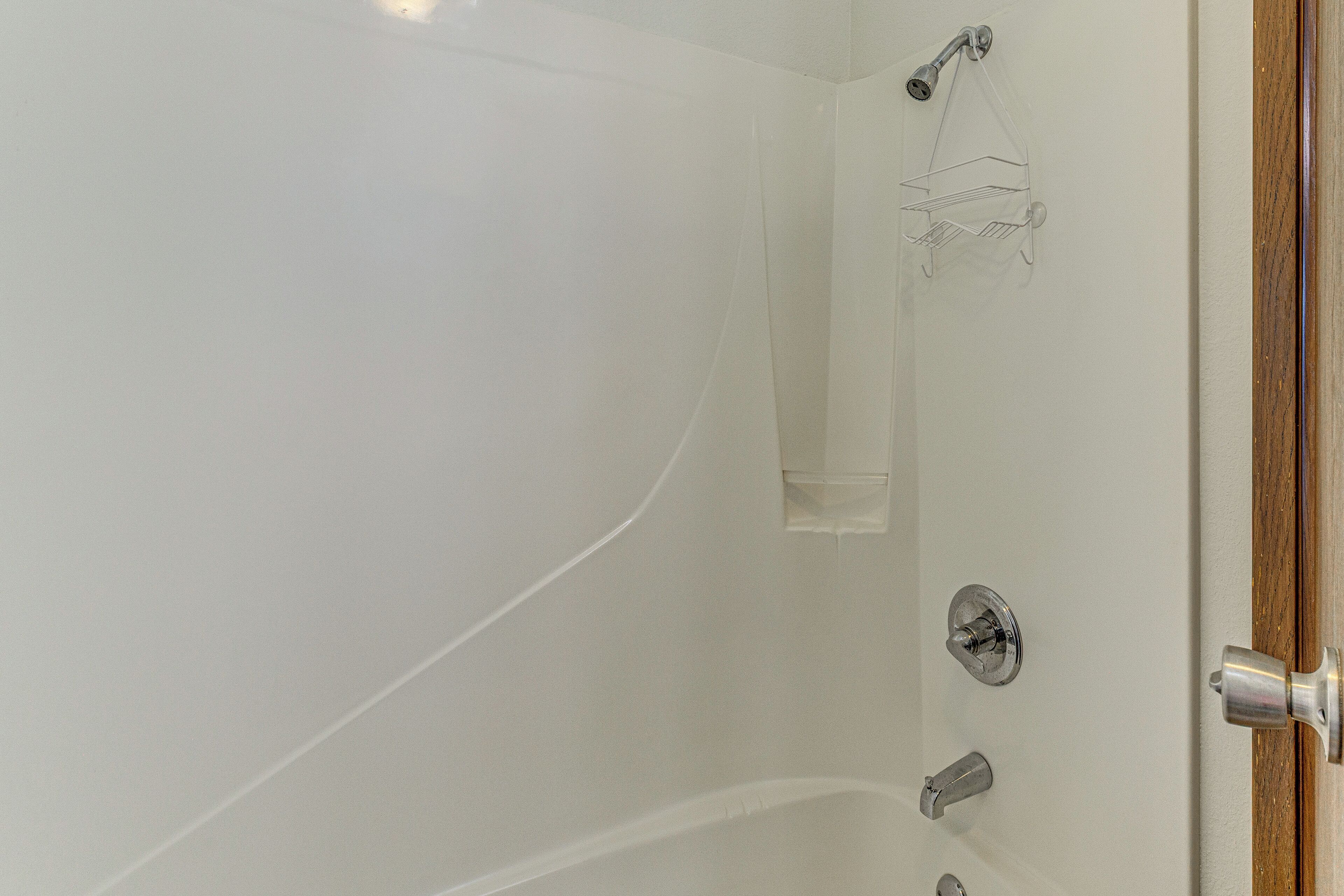 Une salle de bain avec une douche, un porte-serviettes et un cadre de porte en bois.