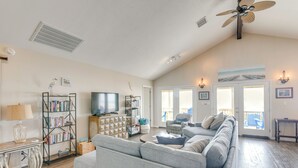 Ein Wohnzimmer mit einer Couch, einem Fernseher, einem Bücherregal und einem Deckenventilator.