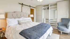 Ein Schlafzimmer mit Bett, Stuhl, Kleiderschrank und Deckenventilator.