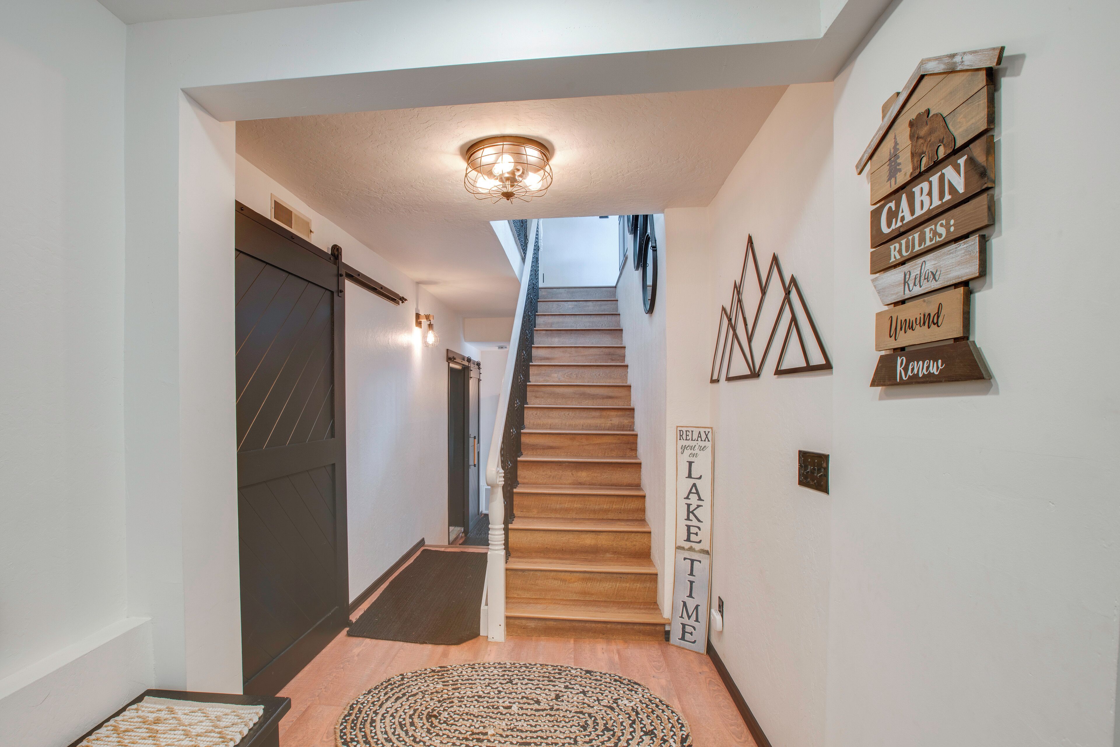 Un escalier menant à une zone abritant des cabanes, avec des marches en bois, une porte sombre et un mur orné de panneaux en bois.