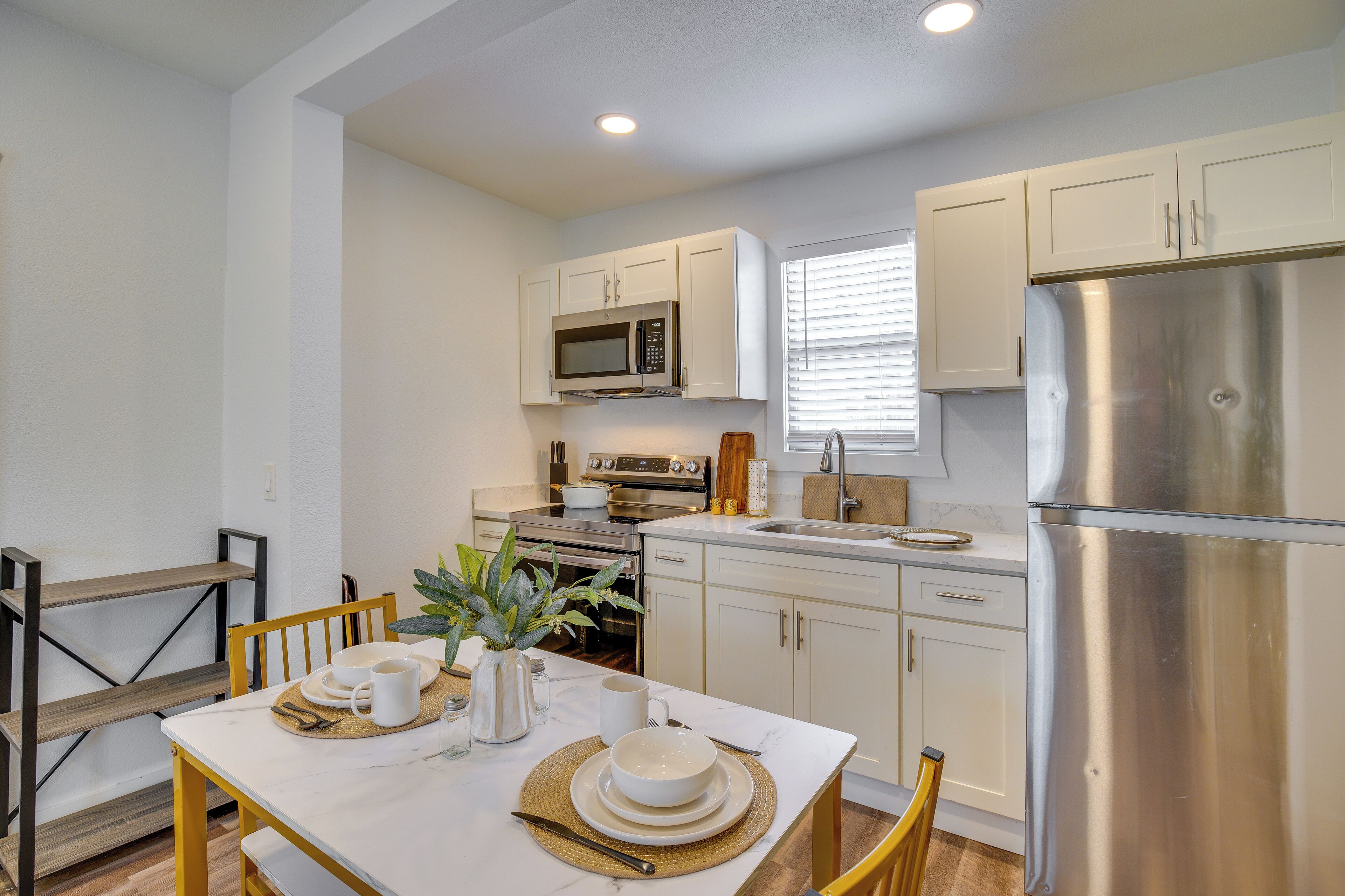 A modern kitchen with white cabinets, stainless steel appliances, and a dining area with a table set for two.