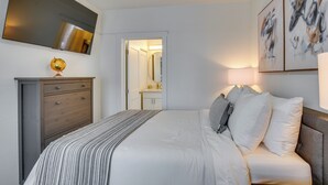 A bedroom with a bed, a dresser, a mirror, and artwork on the wall. - Gateway to Downtown Tacoma! Sleek Couple's Condo (Tacoma)