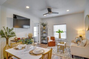 A living room with a dining area, a sofa, a TV, and a ceiling fan.
