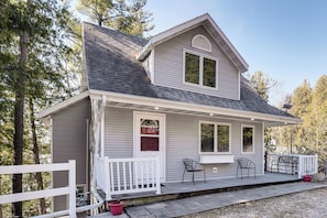 A two-story house with a covered porch, a white fence, and a small garden area. - Elkhart Lake Home w/ Fishing Dock! Family Escape (Elkhart Lake)