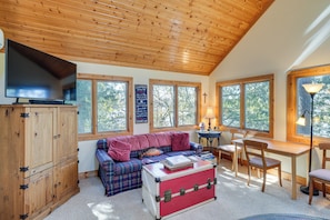A cozy room with a wooden ceiling, a television, a sofa, a table, chairs, and large windows. - Elkhart Lake Home w/ Fishing Dock! Family Escape (Elkhart Lake)
