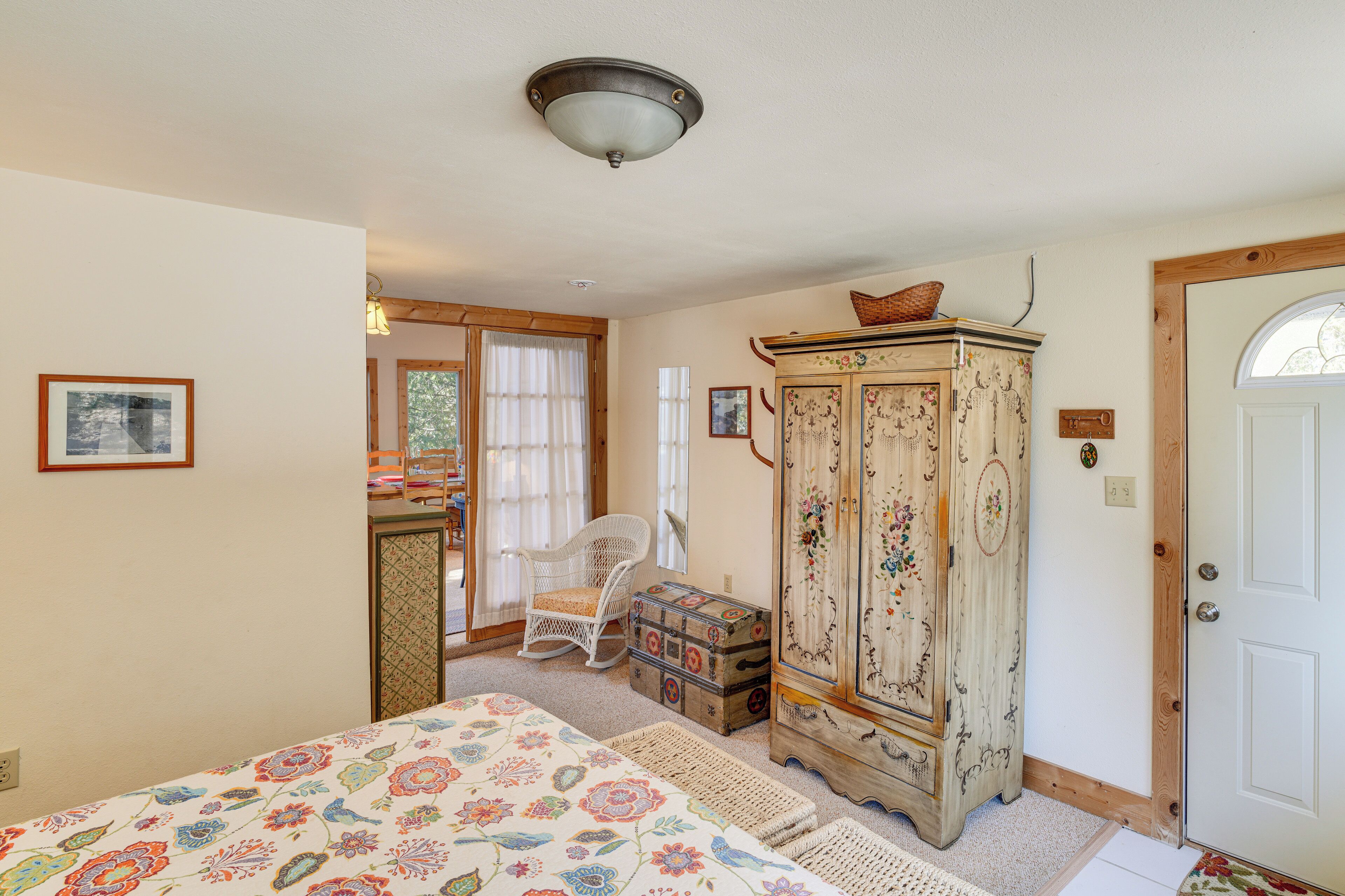 A bedroom with a bed, a dresser, a chair, and a door.