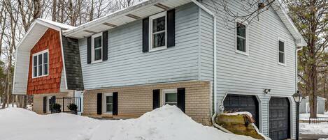 A two-story house with a garage, a small shed, and a snow-covered driveway.