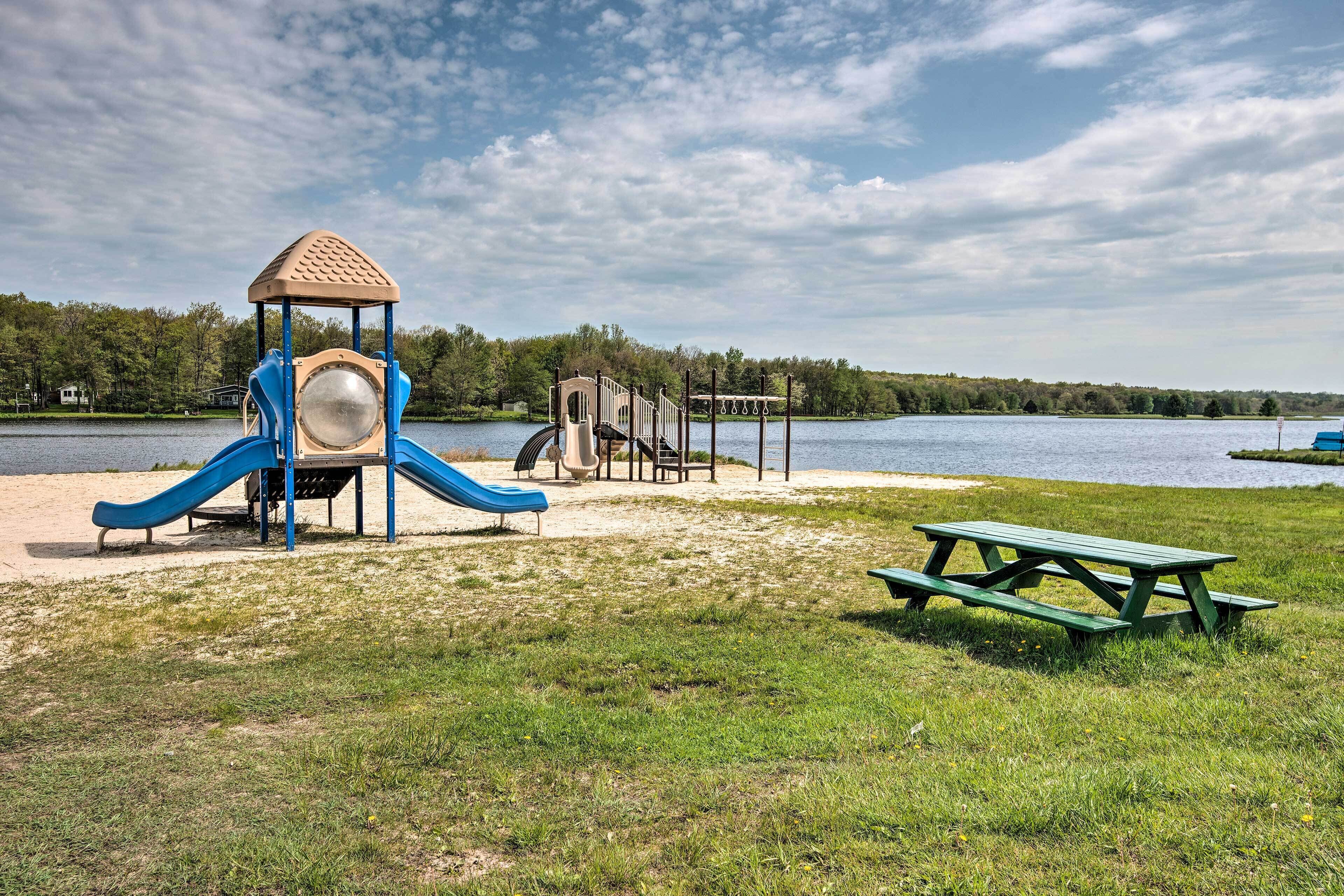 Une aire de jeux avec un toboggan et une structure d’escalade, située près d’un lac.