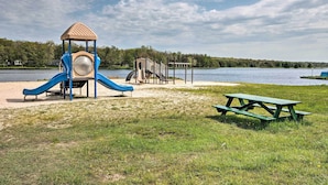 Legeplads med rutschebane og klatrestruktur ved en sø.