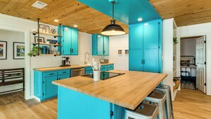 Une cuisine avec un îlot central en bois, des armoires bleues et un luminaire suspendu.