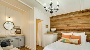 Une chambre à coucher avec une tête de lit en bois, un lit avec une literie blanche, une table de chevet, un miroir et un plafond en bois.