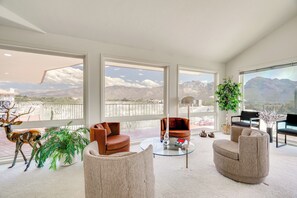 A spacious living room with large windows, a round glass coffee table, and a variety of seating options. - Near Trails: Luxe Mountain-view Retreat in Tucson! (Oro Valley)