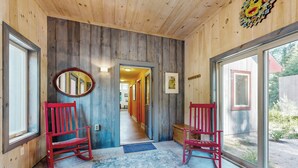 A wooden interior hallway with two red chairs, a blue patterned rug, and a large mirror on the left wall. - Secluded 2 BR Cottage w/ Private W/d, Wifi & Patio (Hancock)