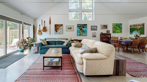 A spacious living room with a high ceiling, large windows, and a variety of artwork on the walls. - Secluded 2 BR Cottage w/ Private W/d, Wifi & Patio (Hancock)