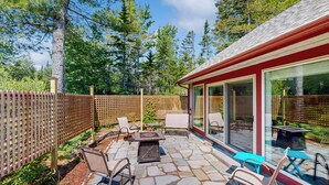 A patio with stone flooring, outdoor furniture, and a glass enclosure. - Secluded 2 BR Cottage w/ Private W/d, Wifi & Patio (Hancock)