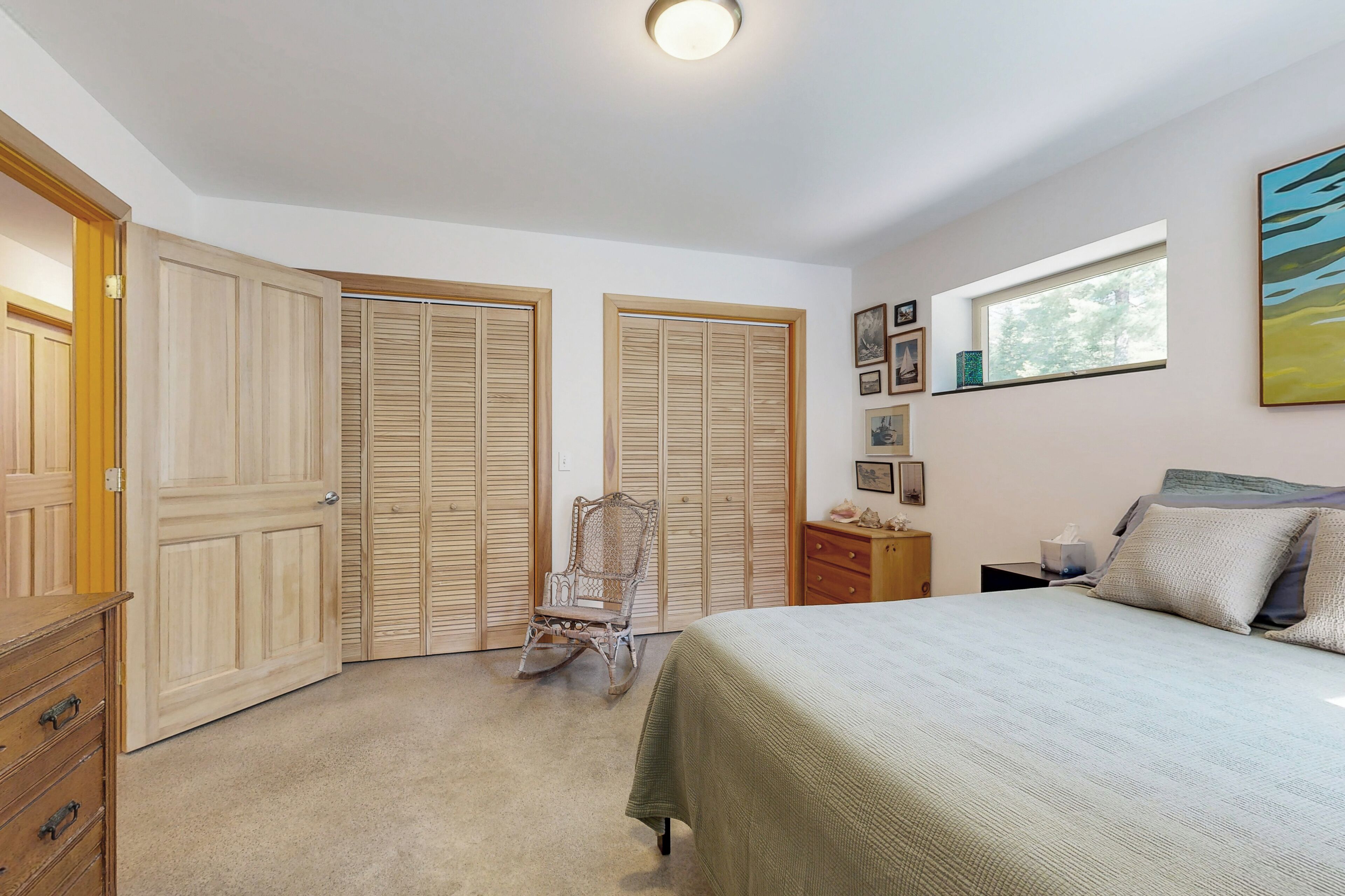 Una camera da letto con un letto, un armadio in legno, una poltrona a dondolo e un comodino con una lampada.
