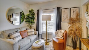 A living room with a sofa, armchair, round mirror, potted plants, floor lamp, and artwork on the wall. - Easy Access to Dtwn Tacoma! Stylish Couple's Condo (Tacoma)