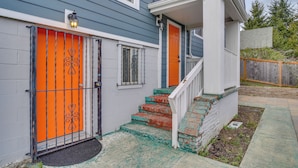 A house with a bright orange door, a white front porch, and a small set of stairs leading to the entrance. - Easy Access to Dtwn Tacoma! Stylish Couple's Condo (Tacoma)